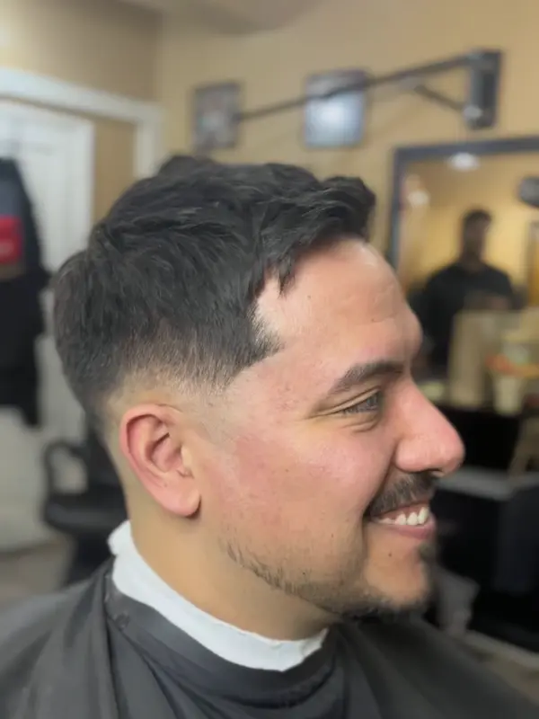 Corte con degradado bajo y barba corta, de perfil