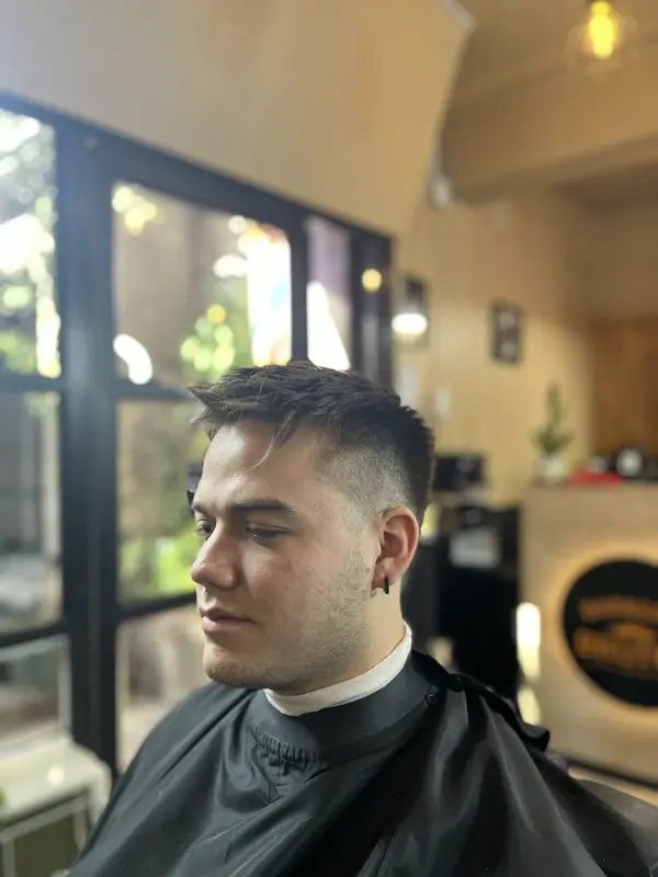 Corte con volumen arriba y lados degradados, junto a la ventana del local