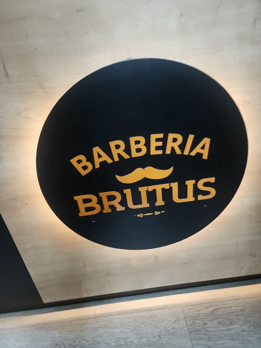 Letrero redondo iluminado de Barbería Brutus sobre la pared